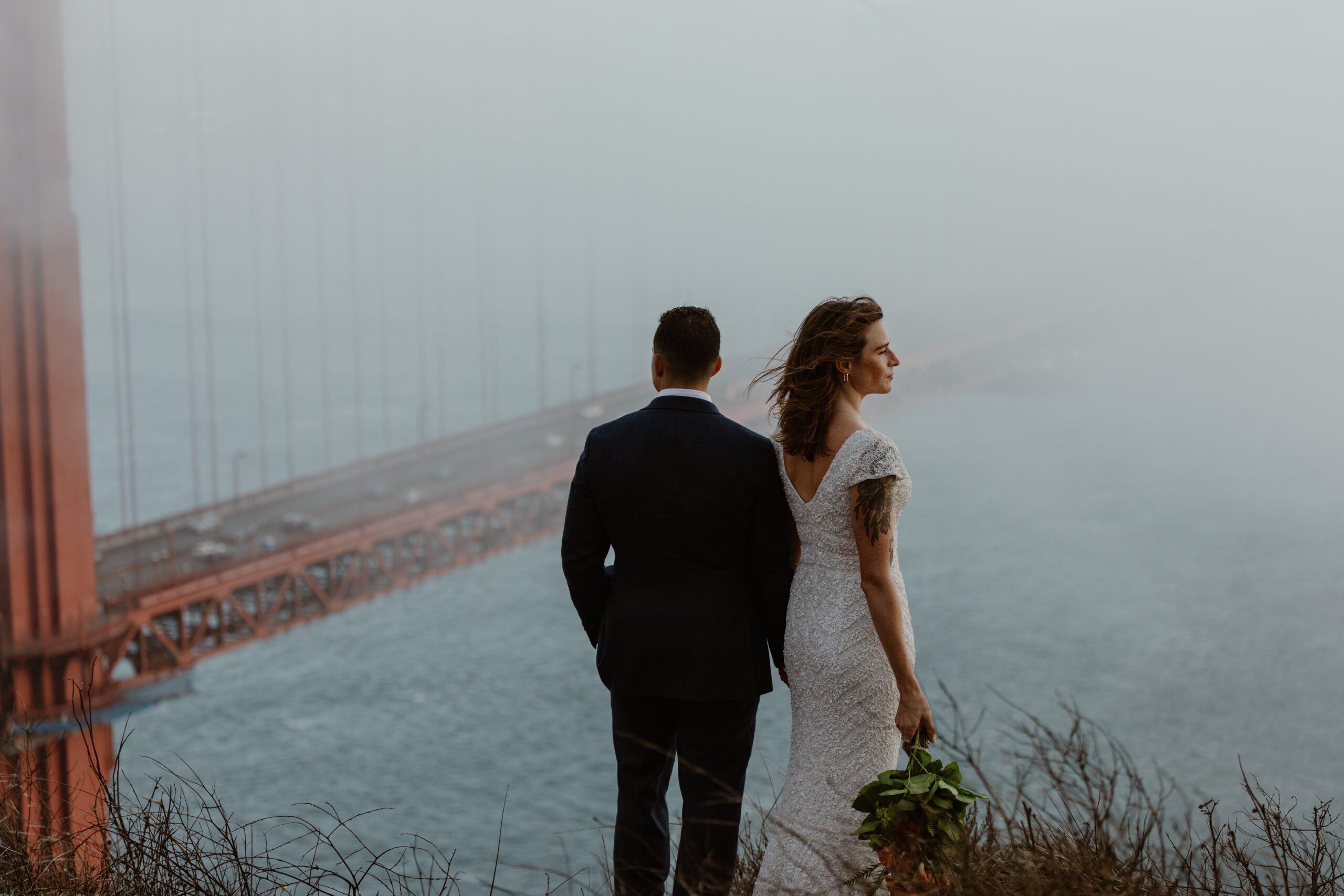 san francisco elopement couple holding each other in front of the golden gate bridge with fog in marin headlands